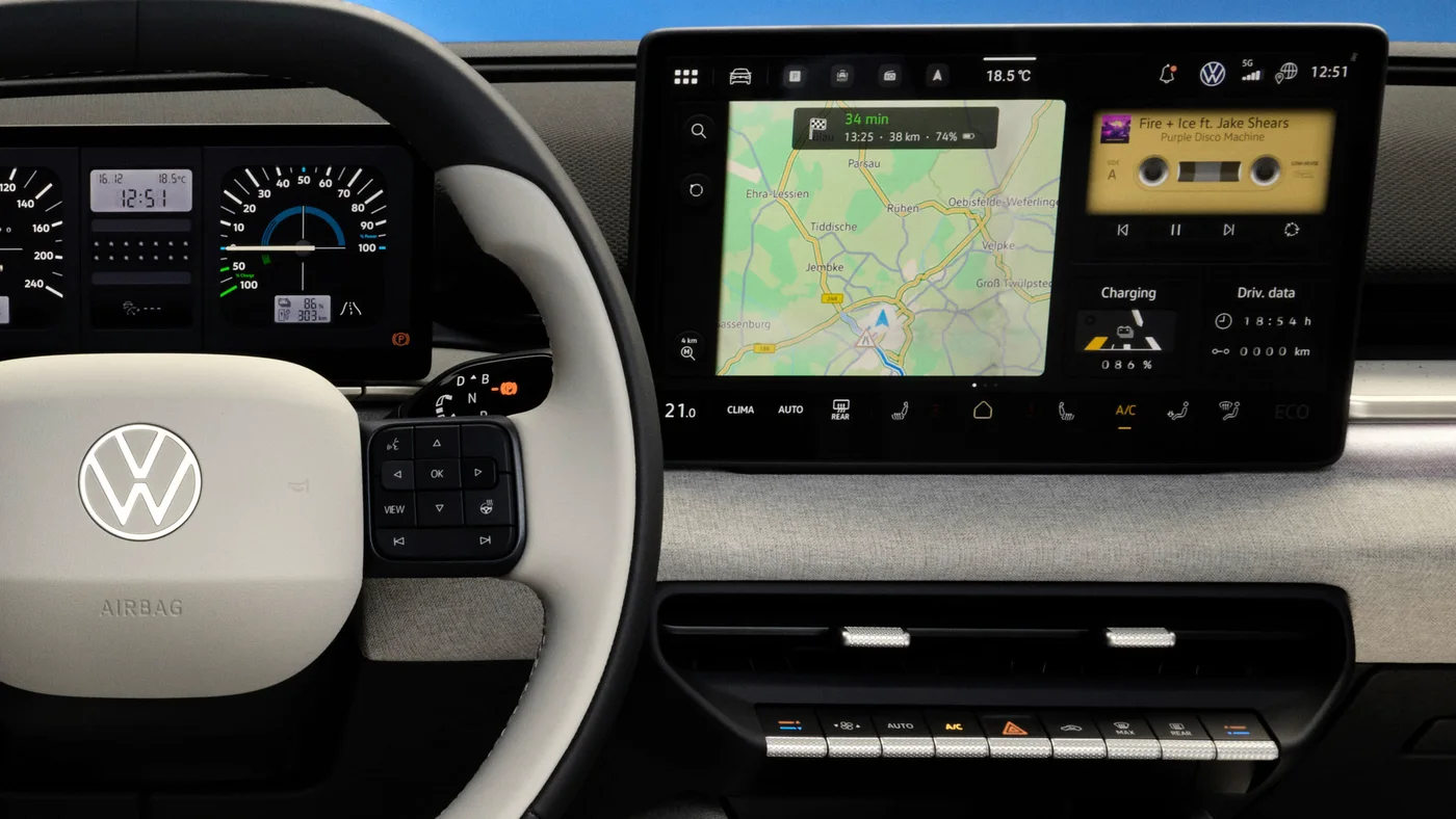Volkswagen ID. Polo console. A row of raised physical buttons sits beneath the touchscreen, including a hazard triangle, and the steering wheel spoke carries a cluster of real pressable buttons.